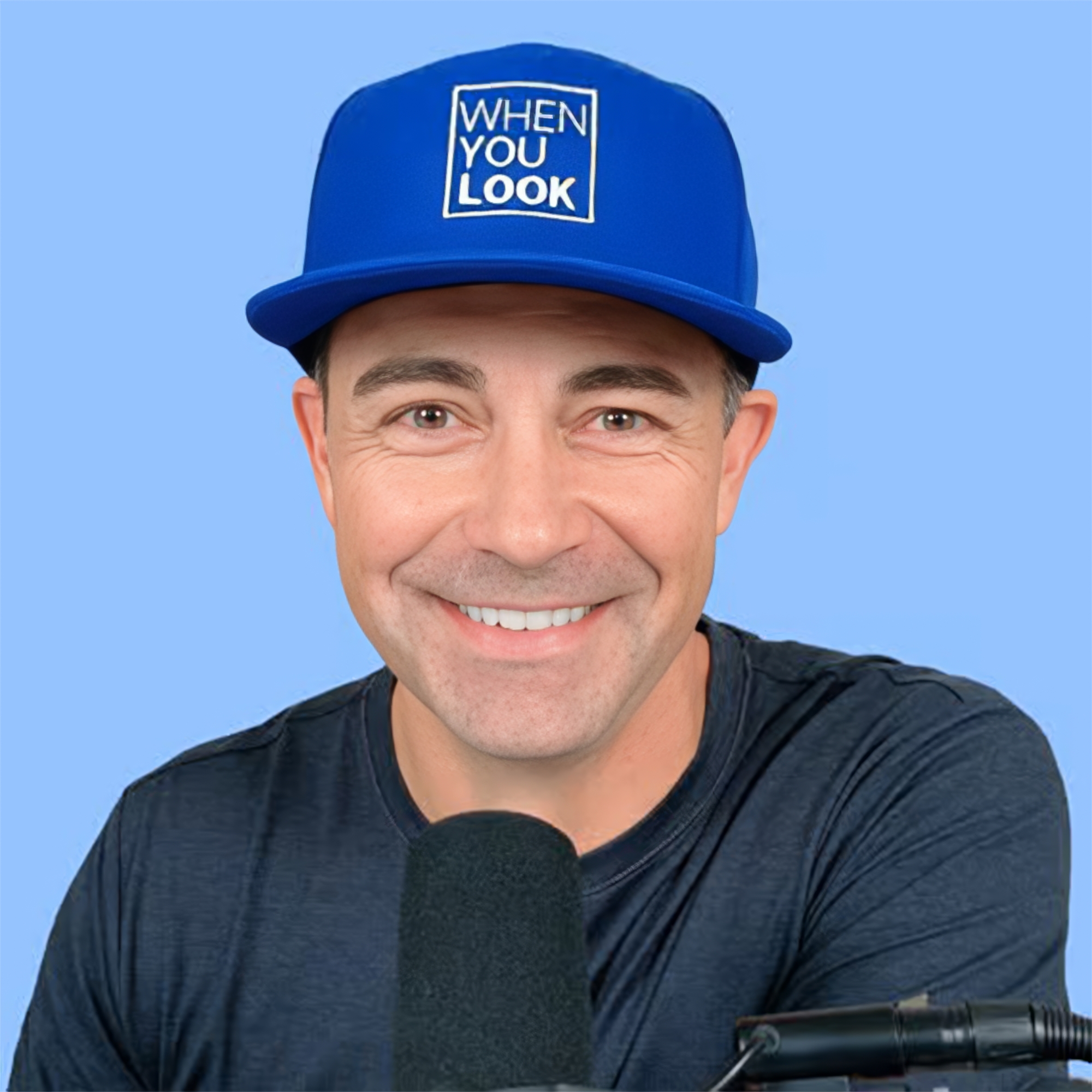 Smiling man Mick Wienholt in a blue cap and dark shirt, speaking into a black podcast microphone against a blue background, sharing his story of finding Jesus after the death of his child. GPS Hope   Grieving Parents Sharing Hope.